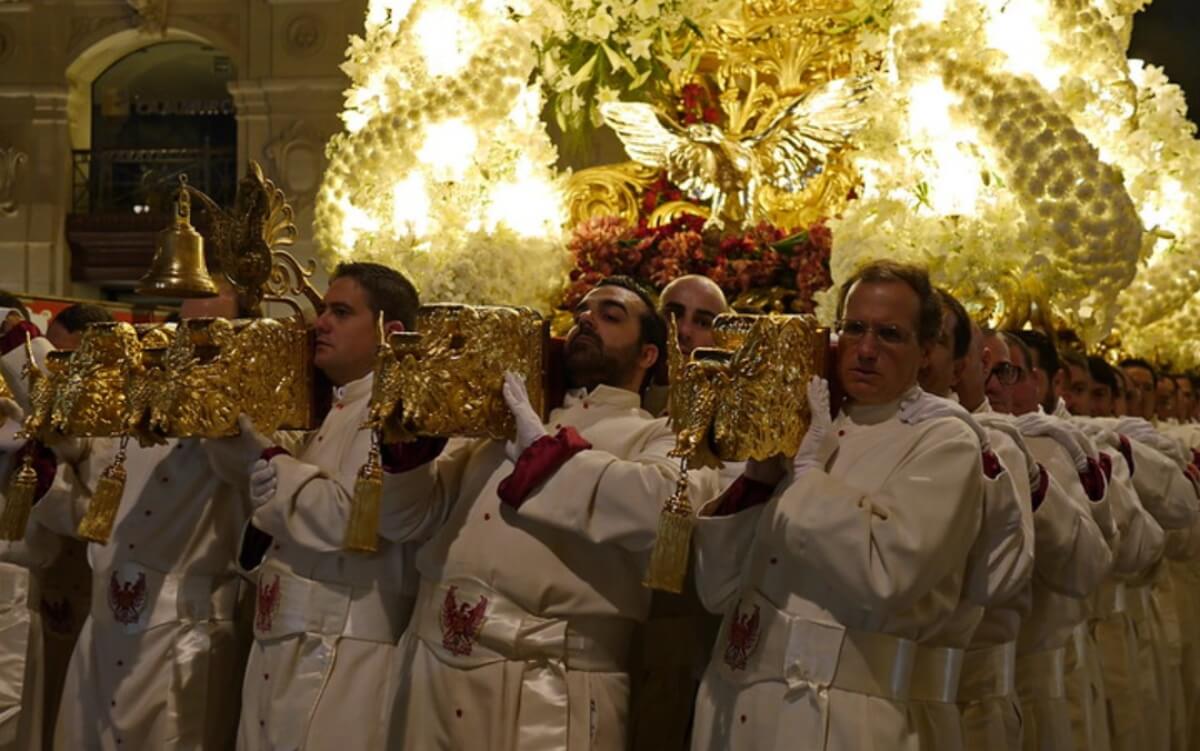 Miembro de cofradía elevando una paso en una procesión de Murcia.
